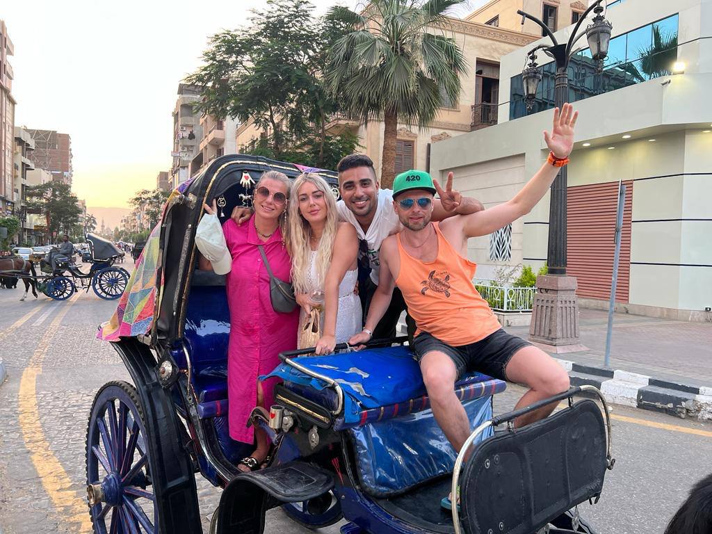 Guests in a horse-drawn carriage on a Luxor street at sunset