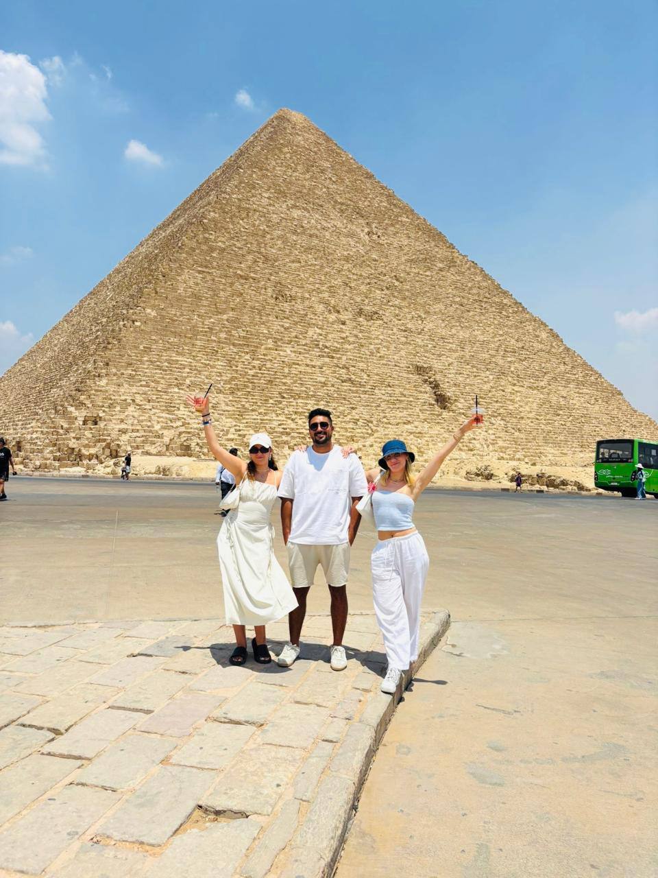 Three guests with their arms raised in front of the Great Pyramid at Giza